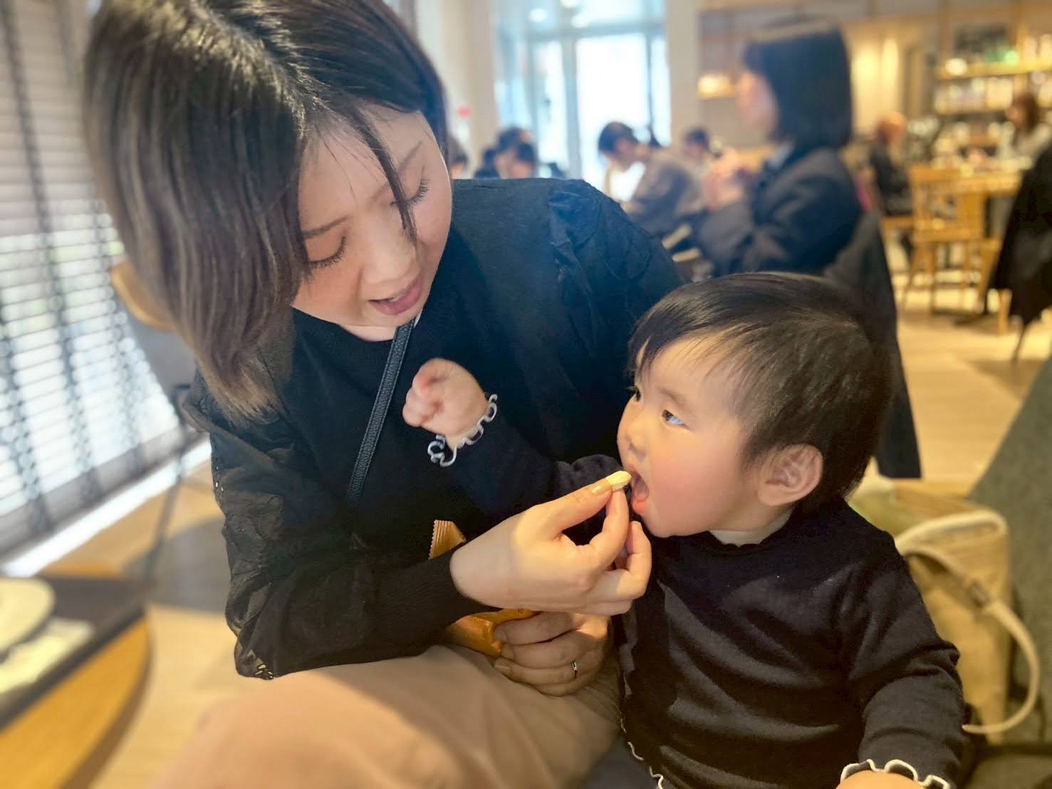 カフェで子どもにおやつを食べさせるお母さん
